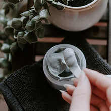 in jar texture shot of SKIN-RG Resurrection polish and mask in 1 skincare product jar on cloth with hand removing product with spatula