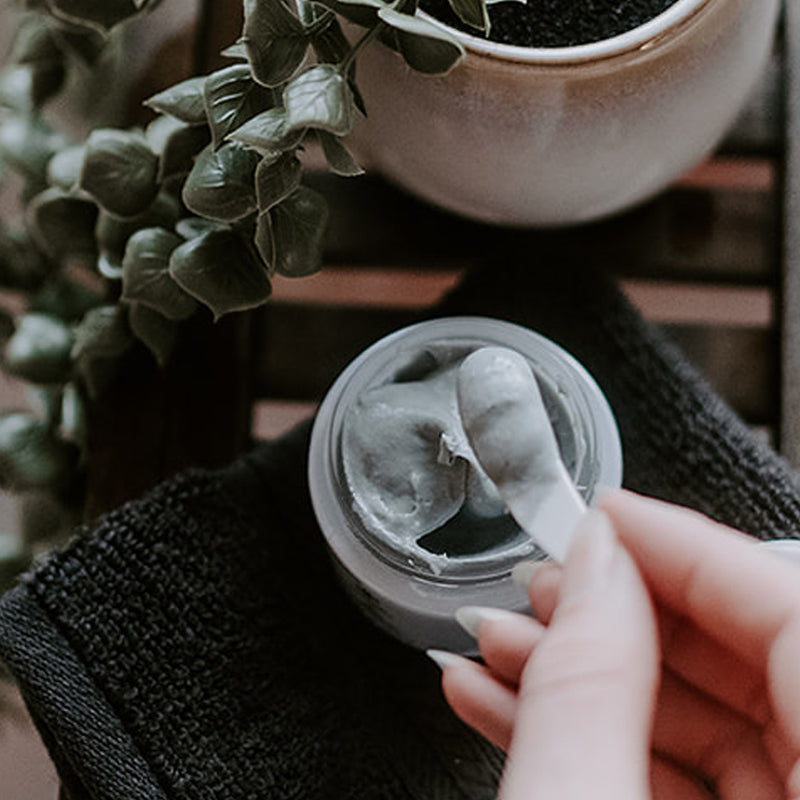 in jar texture shot of SKIN-RG Resurrection polish and mask in 1 skincare product jar on cloth with hand removing product with spatula
