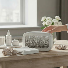 SKIN-RG skincare product set on a wooden table with a hand reaching for it.